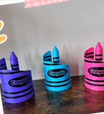 Tres organizadores de escritorio en forma de crayola: morado, azul y rosa